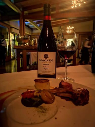 a bottle of wine sitting next to a plate of food at Forum Homini Boutique Hotel in Krugersdorp