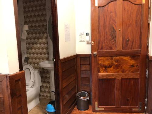 uma casa de banho com um WC e uma porta de madeira em Chiangkhan Hotel em Chiang Khan