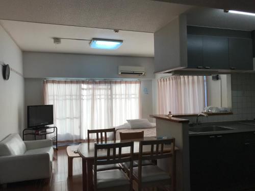 cocina y sala de estar con mesa y sillas. en Weekly Harbourview Mansion Main Building, en Naha