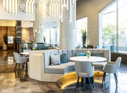 a lobby with a couch and a table and chairs at Ilunion Alcalá Norte in Madrid