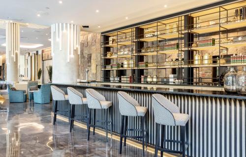 a row of chairs sitting at a bar in a restaurant at Ilunion Alcalá Norte in Madrid