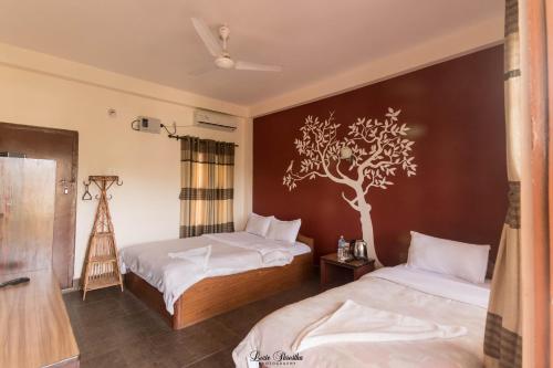 a bedroom with two beds and a tree on the wall at Eden jungle resort in Sauraha