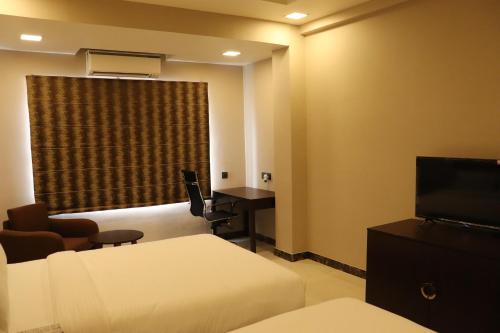 Cette chambre comprend un lit, un bureau et une fenêtre. dans l'établissement Mangal Grand Hotel, à Beāwar