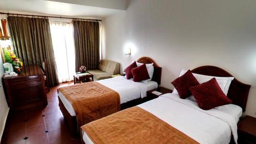 a hotel room with two beds and a chair at KTDC Samudra in Kovalam
