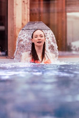 a girl is in the water with an umbrella at Tirol Lodge in Ellmau