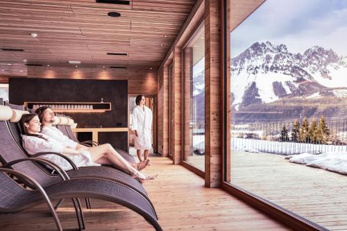 two people sitting in chairs on a balcony with a view of a mountain at Tirol Lodge in Ellmau
