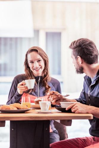 a man and woman sitting at a table drinking coffee at Tirol Lodge in Ellmau