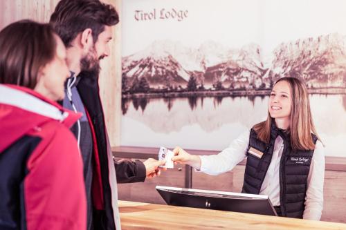 a woman handing a card to a man at a table at Tirol Lodge in Ellmau