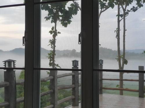 a window looking out at a view of a lake at One khaokho homestay in Khao Kho