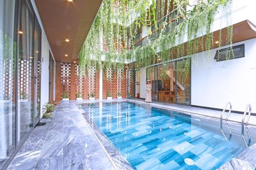 a swimming pool in a building with a large window at MaiChi Villa Hoi An in Hoi An