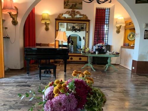 a room with a piano and a table with flowers at Hotel Ficocle in Cervia
