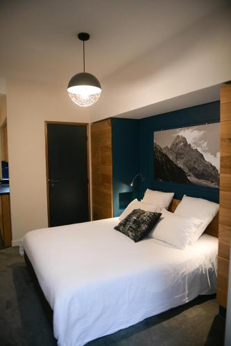 a bedroom with a large white bed and a lamp at Appart'Hotel Aiguille Verte & Spa in Chamonix-Mont-Blanc