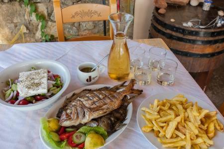 une table avec une assiette de poisson et un bol de frites dans l'établissement Zorbas Rooms, à Frangokastello