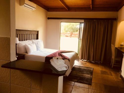 a hotel room with a bed and a large window at Olden Rose Place in Lephalale