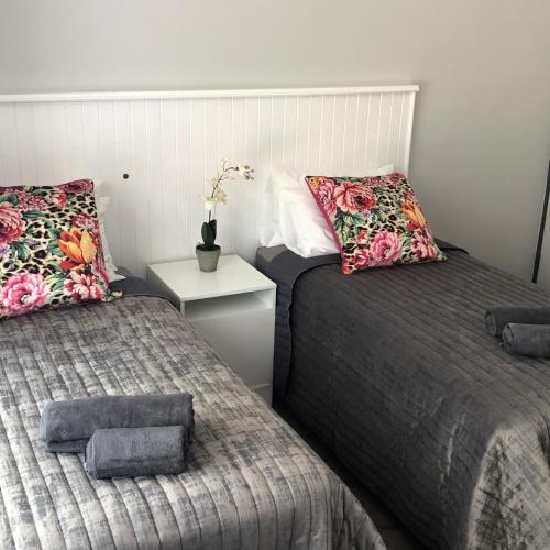 a bedroom with two beds and a table with a night stand at The Red Chimney in Pretoria
