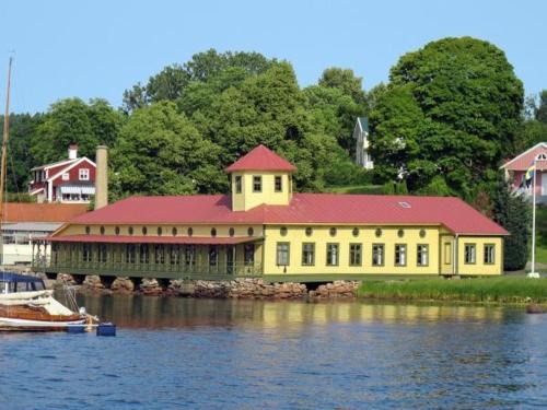 a large yellow building with a red roof on the water at Gustafsbergs Badhotell & Vandrarhem in Uddevalla