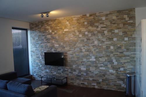 a living room with a brick wall with a flat screen tv at Apartments Klinovec in Loučná pod Klínovcem