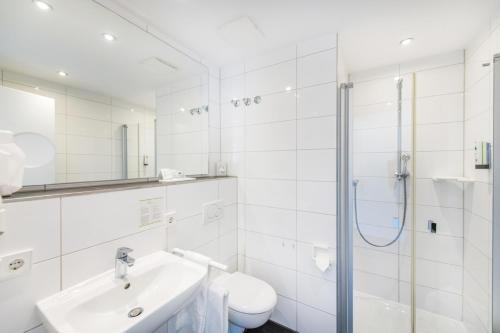 a white bathroom with a sink and a toilet at Hotel Cochemer Jung in Cochem