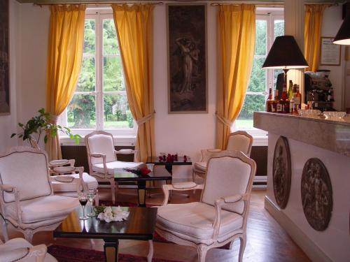 a living room with chairs and tables and a fireplace at Hostellerie Du Château Les Muids in La Ferté-Saint-Aubin