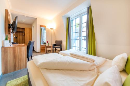 een woonkamer met 2 witte bedden in een kamer bij Hotel Cochemer Jung in Cochem