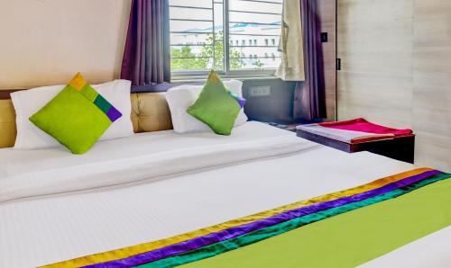 a large white bed with colorful pillows and a window at Itsy Hotels The Villa Retreat in Siliguri
