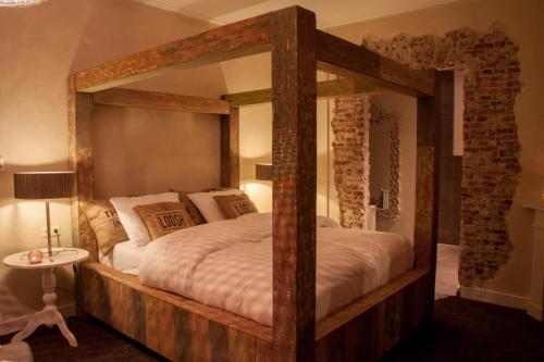a bedroom with a large wooden bed with a large mirror at Hotel Huis van Bewaring - Bijzonder boutique hotel in historisch pand in Almelo