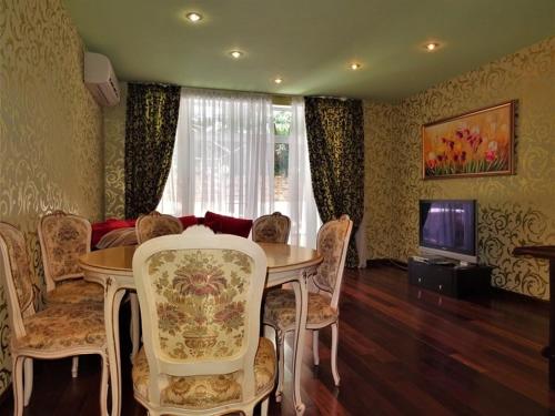 a living room with a table and chairs and a television at Royal Nikita Apartments in Nikita