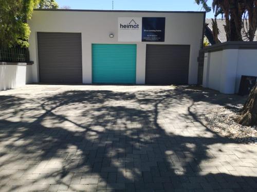 a building with two garage doors in a driveway at Heimat Guesthouse in Welkom