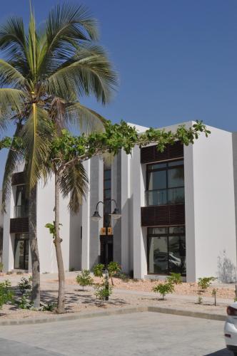 un bâtiment avec deux palmiers devant lui dans l'établissement Luxury Suite - Amazing Views & Lovely Garden, à Salalah