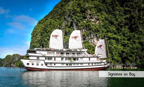 a boat in the water next to a mountain at Signature Halong Cruise in Ha Long