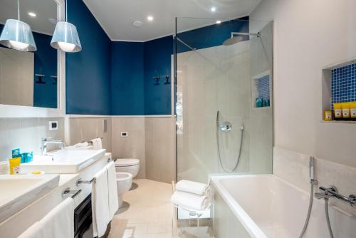 y baño con bañera, lavamanos y ducha. en Forte Village Resort - Il Castello en Santa Margherita di Pula