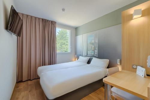 una habitación de hotel con una gran cama blanca y una ventana en B&B HOTEL Lyon Centre Monplaisir, en Lyon