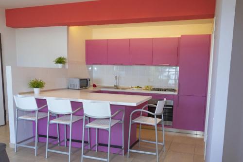a kitchen with purple cabinets and white stools at Casa e Mare in Montignano
