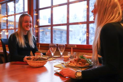 
two women sitting at a table with plates of food at Kakslauttanen Arctic Resort - Igloos and Chalets in Saariselka
