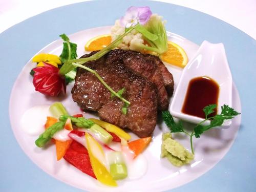 a plate of food with a piece of meat and vegetables at HOTEL W-PREMIUM -W GROUP HOTELS and RESORTS- in Koshigaya