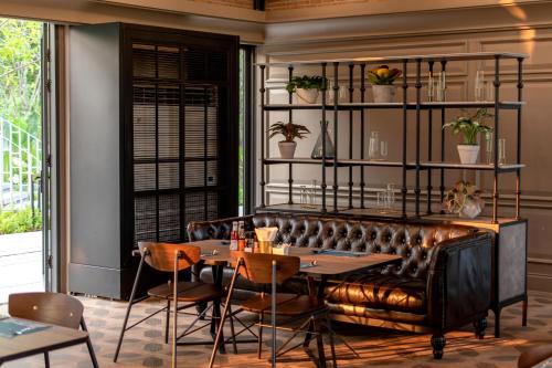 a restaurant with a leather bench and a table and chairs at Hotel Labaris Khao Yai in Mu Si