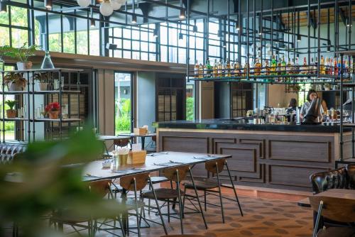 a restaurant with tables and chairs and a bar at Hotel Labaris Khao Yai in Mu Si