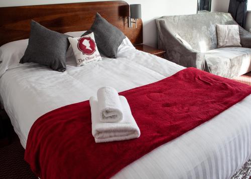 a bed with two towels on a red blanket at Oliver Twist Country Inn in Wisbech