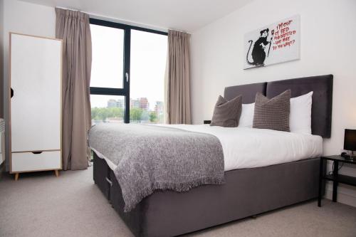 a bedroom with a large bed and a large window at Open Key Apartments in Liverpool