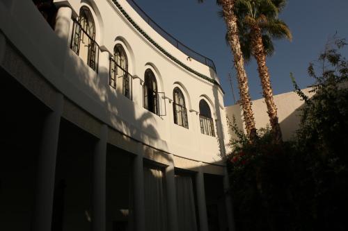 a white building with a palm tree in front of it at Riad Chergui in Marrakech