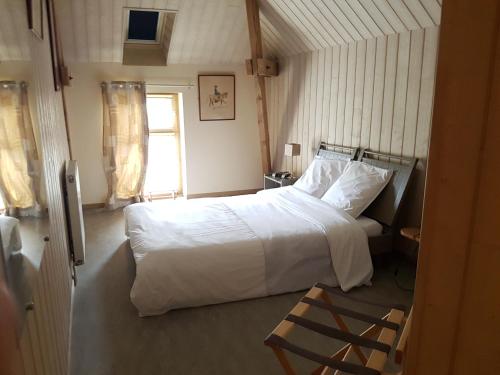a bedroom with a white bed and a window at Logis Relais Des Caillères in Saint Pavace