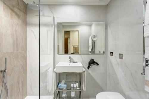 a white bathroom with a sink and a shower at Marcella Royal Hotel - Rooftop Garden in Rome