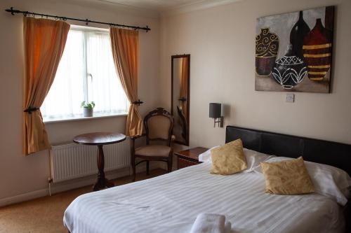a bedroom with a bed and a chair and a window at Oliver Twist Country Inn in Wisbech