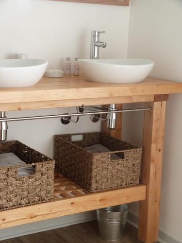 La salle de bains est pourvue d'une coiffeuse en bois avec 2 lavabos et des paniers. dans l'établissement Chambres d'hôtes Le Cartounier, à Pinel-Hauterive