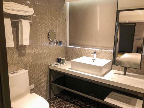 a bathroom with a sink and a toilet and a mirror at City Suites - Taoyuan Station in Taoyuan