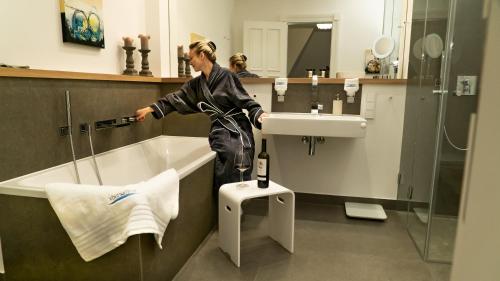 eine Frau, die neben einer Badewanne im Bad steht in der Unterkunft FIRST im FIRST Sellin, Penthouse Paradies am Meer in Ostseebad Sellin