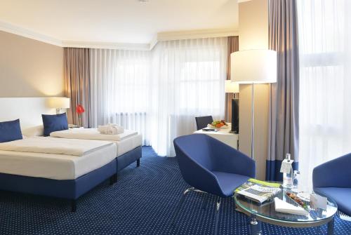 a hotel room with a bed and a table and chairs at relexa hotel Schatten Stuttgart in Stuttgart