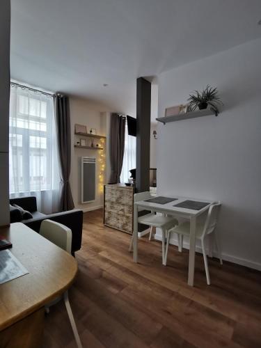 un salon avec une table et des chaises blanches dans l'établissement Le cocon du centre ville, à Lens