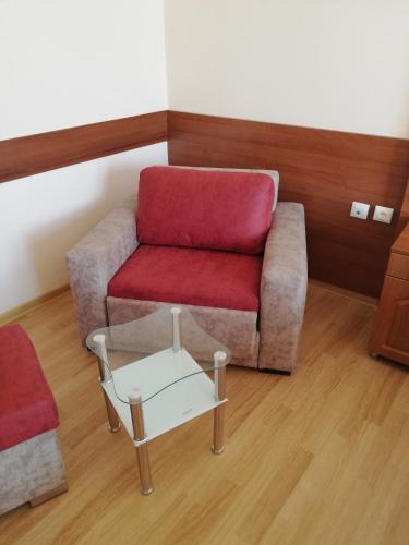 a living room with a red chair and a coffee table at Balneo and SPA Complex MINERAL YAGODA in Yagoda