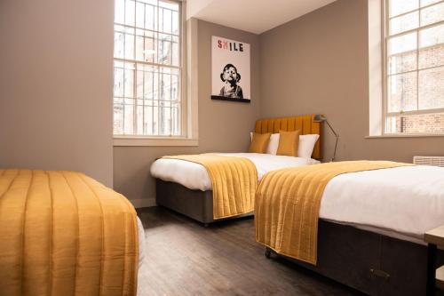 a bedroom with two beds and two windows at York Street Studios in Liverpool